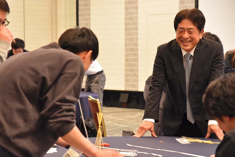 マシュマロチャレンジに挑戦する研修生とそれを笑顔で見守る研修講師