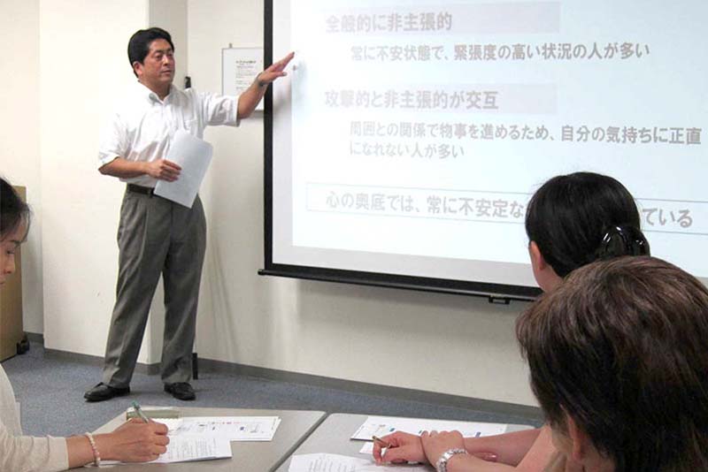 ビジネスセミナーでスライド映像を指差し説明する研修講師